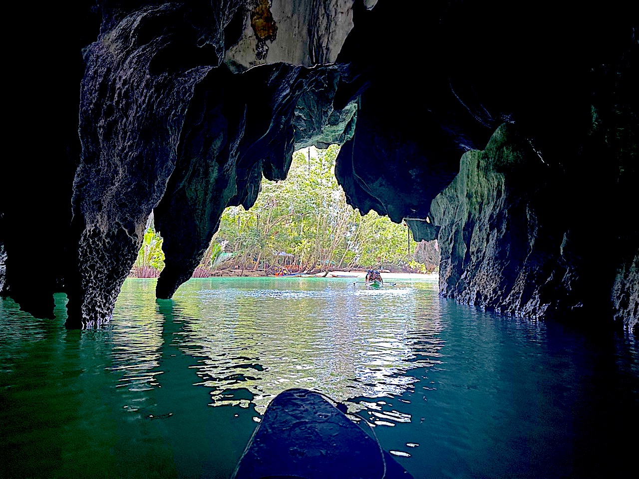 photo-of-front-of-canoe-on-blue-water-leaving-Underground-River-Palawan-with-rock-formations-above